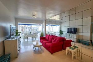 a living room with a red couch and a table at Beachfront Apartment with Sea Views & Pool - El Puig in El Puig +24 photos