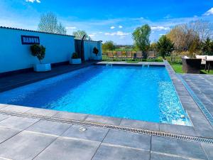 a swimming pool with blue water in front of a building at Banova Vendégház in Császártöltés