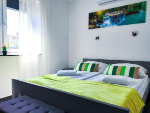 a bedroom with a bed with a green blanket on it at Banova Vendégház in Császártöltés