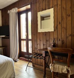a bedroom with a wooden wall with a mirror and a desk at Hotel PIAN DEL SOLE Claviere in Claviere