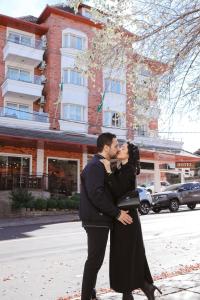 a man and woman kissing in front of a street at Hotel Glamour da Serra in Gramado