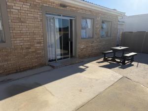 a patio with a bench next to a brick building at The041Stay in Gqeberha