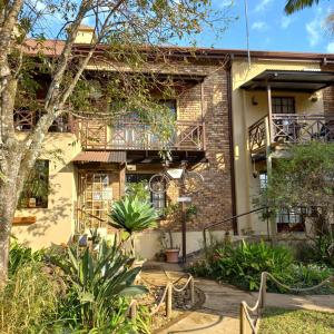 a brick house with a balcony and plants at Autumn Breeze Manor Guest House in Graskop