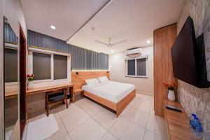 a bedroom with a bed and a desk and a tv at Harvey's Hotel in Hyderabad