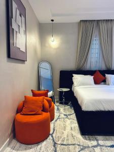 a bedroom with a bed and an orange chair at Diah Homes Apartment in Benin City