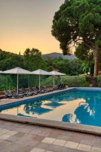 a swimming pool with chairs and umbrellas at Balneari Termes Victòria in Caldes de Montbui