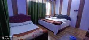a bedroom with two beds and a window with green curtains at Hotel green chinar & restaurant in Srinagar
