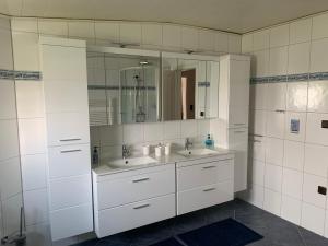 a white bathroom with two sinks and a mirror at Privatzimmer Guhl in Munster +25 photos