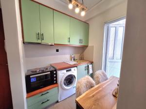 a kitchen with green cabinets and a washing machine at The Handcrafted Haven 2 min to Central Square in Missolonghi