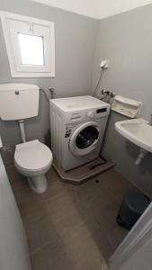 a bathroom with a toilet and a washing machine at Maritsa's Cozy Apartment in Mytilinioí +16 photos