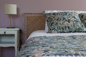 a bed with a pillow and a lamp on a side table at Au Jardin de Mireille in Leffrinkhoucke