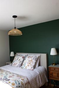 a bedroom with a green wall and a bed at Au Jardin de Mireille in Leffrinkhoucke