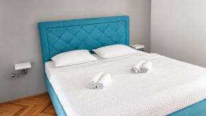 a bed with a blue headboard and two slippersituresvisoromaly at Apartment Nana in Primošten