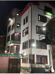 a tall white building with windows at night at Hotel green chinar & restaurant in Srinagar