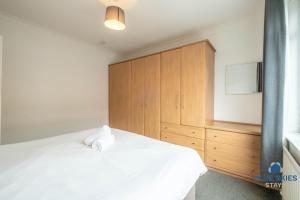 a bedroom with a white bed and a wooden cabinet at Millfield House by Blue Skies Stays in Middlesbrough +7 photos