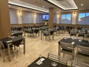 a restaurant with black tables and chairs and a tv at Hotel Sierra de Huesa in Huesa