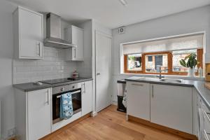 a kitchen with white cabinets and a sink and a window at Finest Retreats - Poundtree in Wherwell +15 photos