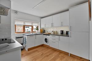 a kitchen with white cabinets and a washer and dryer at Finest Retreats - Poundtree in Wherwell