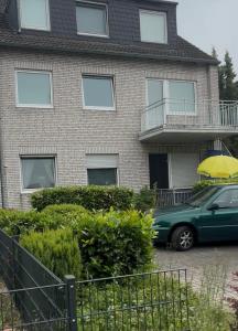 a green car parked in front of a house with a yellow umbrella at Apartments an der Messe in Düsseldorf