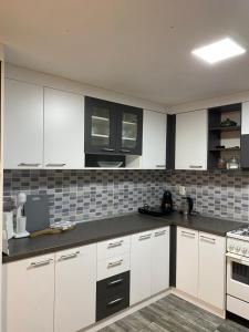 a kitchen with white cabinets and black counter tops at Kuca za odmor-Tisa Hideaway in Turija