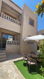 a patio with a table and chairs and an umbrella at Chalet in La mera north coast in Zāwiyat al ‘Awwāmah