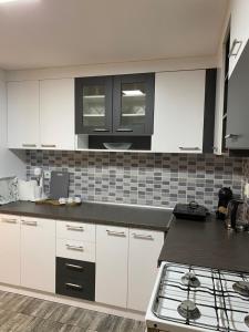 a kitchen with white cabinets and black counter tops at Kuca za odmor-Tisa Hideaway in Turija