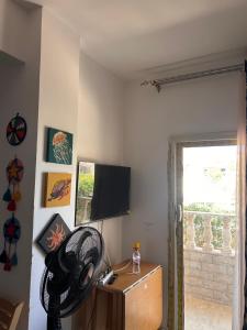 a room with a flat screen tv and a fan at Chalet in La mera north coast in Zāwiyat al ‘Awwāmah