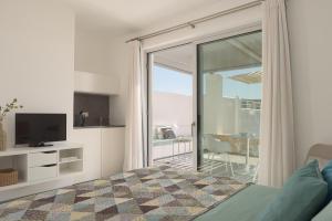 a bedroom with a bed and a television and a balcony at Galini Breeze in Agia Galini