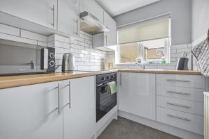 a white kitchen with a microwave and a stove at Saint Johns Rest in Biggleswade