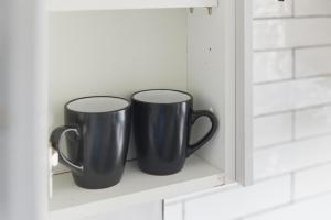 two black coffee mugs sitting on a shelf at Saint Johns Rest in Biggleswade