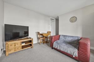 a living room with a couch and a tv and a table at Saint Johns Rest in Biggleswade