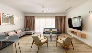 a living room with a couch and chairs and a tv at Voilà Beau Vallon in Beau Vallon