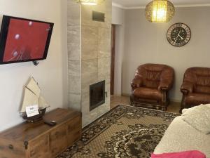 a living room with two chairs and a flat screen tv at Golden House in Khust