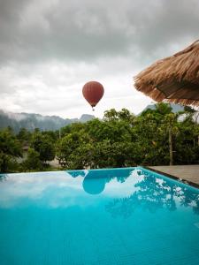 a hot air balloon flying in the sky over a pool at T&T Bungalow in Ban Khouaphan