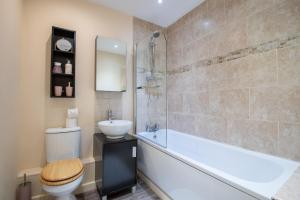 a bathroom with a tub and a sink and a toilet at No12, Modern 2 Bedroom Apartment in Mansfield