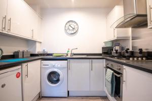 a kitchen with a washing machine and a clock on the wall at No12, Modern 2 Bedroom Apartment in Mansfield