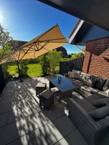 a patio with a table and chairs and an umbrella at Nordseetraum - Ferienhaus Wolke in Friedrichskoog