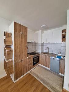 a kitchen with wooden cabinets and a sink and a dishwasher at Apartment Stup Sarajevo in Sarajevo