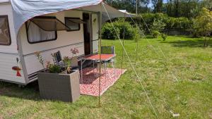 a table and a chair in front of a caravan at Caravane Cosy - 5min Circuit 24h du Mans in Changé