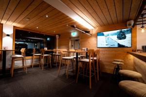 a bar with stools and a tv on a wall at Chalet Sepp in Belalp