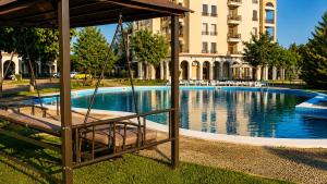 a swing in front of a swimming pool with a building at Guest House Forest 20 in Balchik