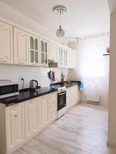 a kitchen with white cabinets and black counter tops at Darkhan apartment in Darhan