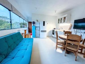 a living room with a blue couch and a kitchen at Sheeps Family - Loft, Casa e Apartamento para Temporada - Praia do Rosa in Praia do Rosa