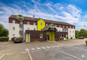 a large building with a parking lot in front of it at B&B HOTEL Beaune Sud 2 in Beaune