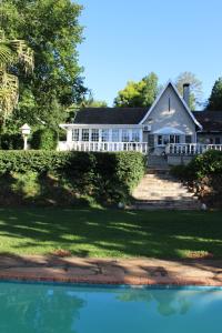 a white house with a swimming pool in front of it at A Garden Suite B&B in Pietermaritzburg