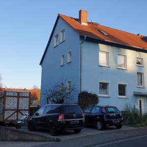 two cars parked in front of a blue house at Ferienwohnung Bad Vilbel in Bad Vilbel
