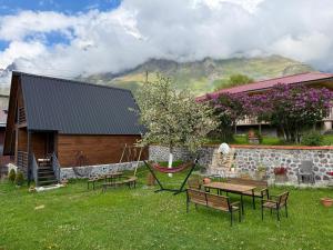 a yard with benches and a hammock in front of a house at Golden Star Cottage in Kazbegi