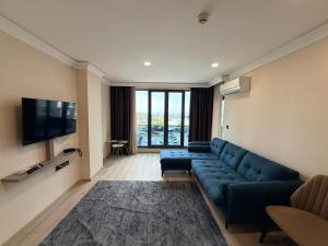 a living room with a blue couch and a flat screen tv at Rena Grand Residence & Suit in Trabzon