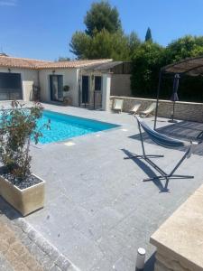 a swimming pool with a hammock next to a house at Gîte chez l'habitant indépendant "La villa des ocres" in Gargas +6 photos
