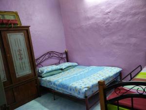 - une chambre avec un lit et un mur violet dans l'établissement Homestay Izzahrah Arau UNIFI, Fully Aircond, à Arau